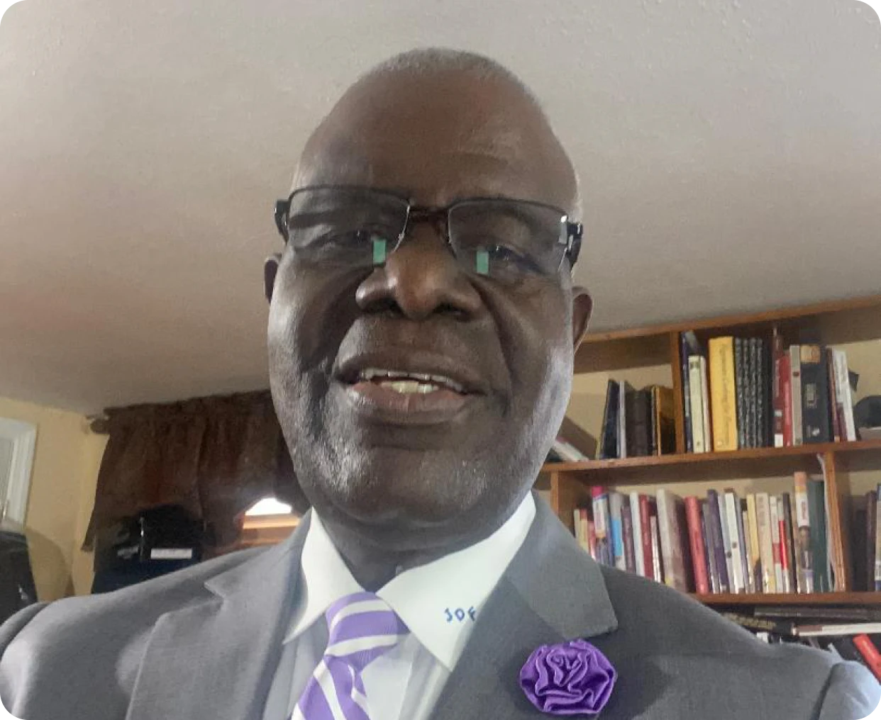 Man smiling in suit with purple tie.