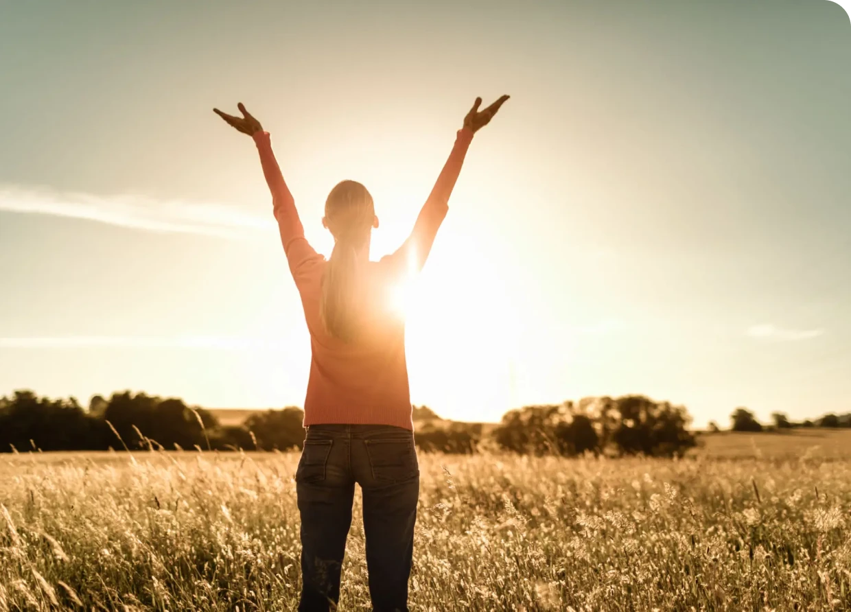 Person embracing sunlight in open field.
